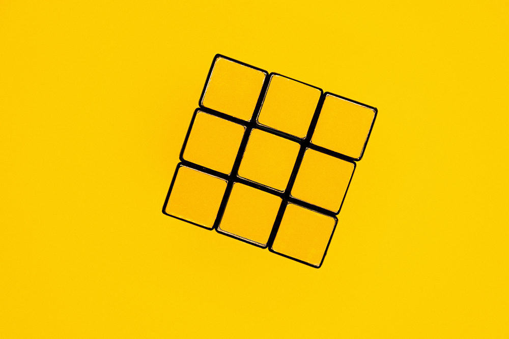 A yellow rubick's cube against a plain yellow background